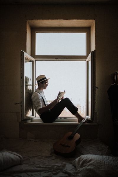 The man sitting in the window reading a book
